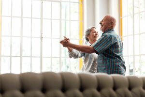 senior-55-couple-dancing-in-front-of-sofa-at-retirement-community-in-Holland-PA-lg